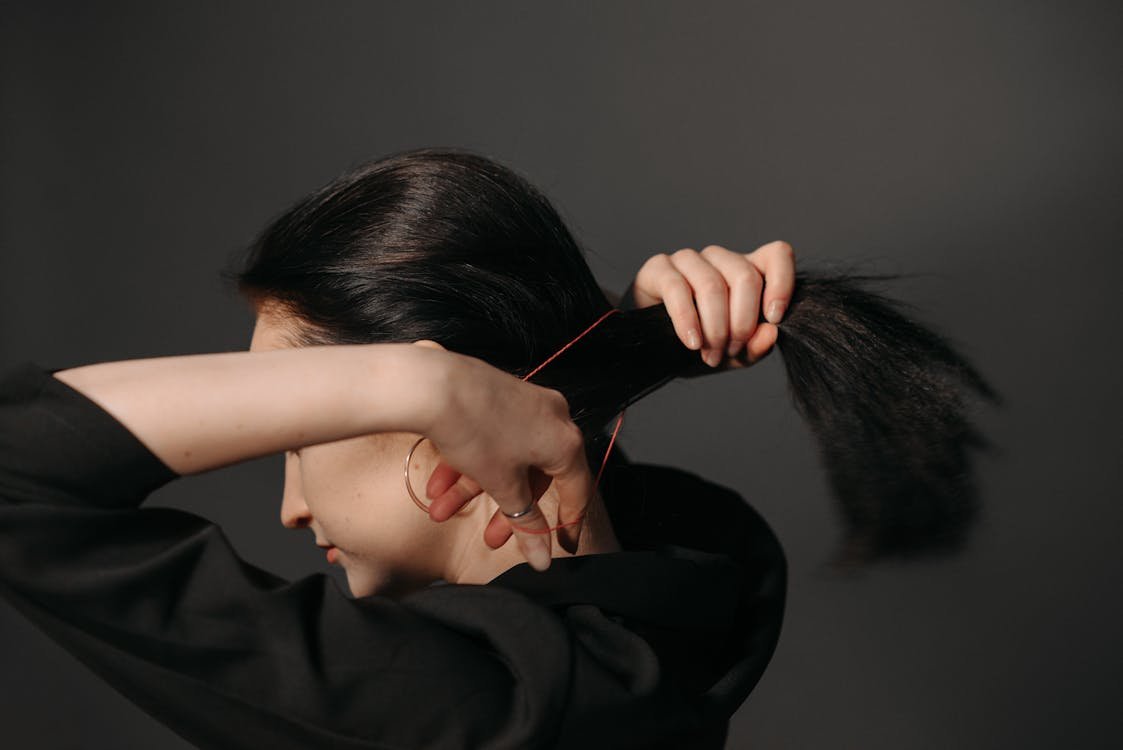 Free A Woman Tying her Hair using a Rubber Band Stock Photo