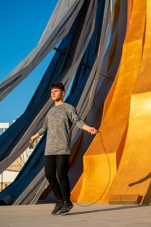 Free Man jumping rope outdoors in Ankara, Türkiye against modern architectural backdrop. Stock Photo