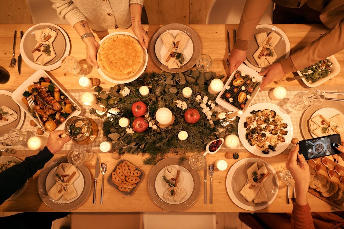 Free A beautifully decorated holiday dinner table with festive food, decor, and people capturing memories. Stock Photo