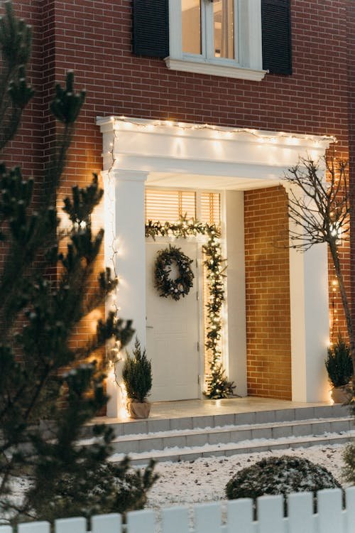 Free Charming brick house entrance decorated with Christmas wreath and lights in winter. Stock Photo