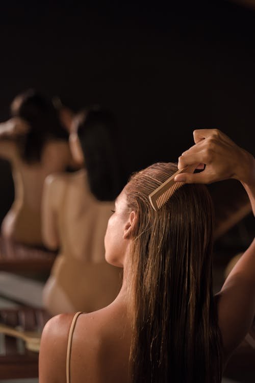 Free Back view of women grooming hair with combs in a serene spa setting, promoting self-care. Stock Photo